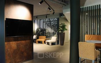 Modern interior at Keulenstraat 12, Deventer with stylish seating, wall art, and a mounted TV; contemporary office space rental.