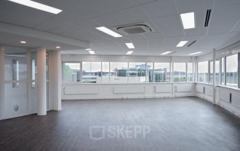 Interior of office space located at Keulenstraat 12 in Deventer, featuring large windows, grey flooring, and white walls, ideal for office space rental.