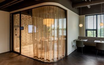 Modern office to rent at Diemerhof 42, Diemen featuring glass-walled meeting room with cozy seating and adjacent collaborative workspace.