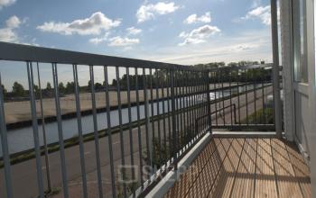 Balcony view from the office space at Weesperstraat 118, Diemen, overlooking a canal and surrounding greenery.
