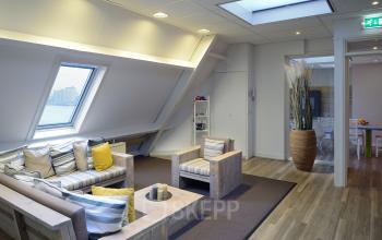 algemene ruimte kantoorpand dordrecht loungeruimte informeel overleggen banken raam uitzicht deuropening plant vloerkleed parket