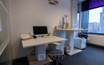 Bright office space with desks, computer monitors, and large windows located at Berglaan 4-8, Drachten, offering an inviting workspace for rent.