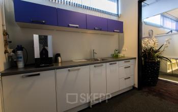 Pantry area with modern cabinets at Berglaan 4-8 in Drachten, suitable for office space rental, includes a coffee machine, sink, and counter space.