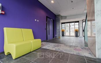 Modern office entrance at Berglaan 4-8 in Drachten with stylish seating and vibrant purple wall.
