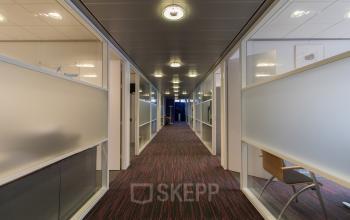 Office to rent at Berglaan 4-8, Drachten, featuring a corridor with modern lighting, frosted glass partitions, and a clean carpeted floor.