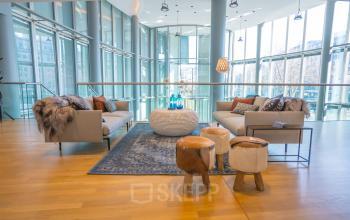 Modernes Büro in Graf-Adolf-Platz 15, Düsseldorf Altstadt (Königsallee) mit stilvoller Wohnzimmeratmosphäre. Viel natürliches Licht und Glaswände, Holzboden, Sofas und Hocker für informelle Treffen.