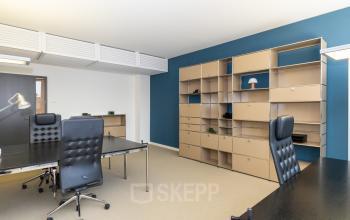 Moderner Büroraum in der Breite Straße 3, Düsseldorf Altstadt, mit blauer Wand und Regalen. Bürofläche mieten.