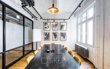 Moderner Besprechungsraum im Büro in der Grünstraße 15, Düsseldorf Altstadt (Königsallee), mit Holztisch, gelben Stühlen und Pflanzenbildern an der Wand.