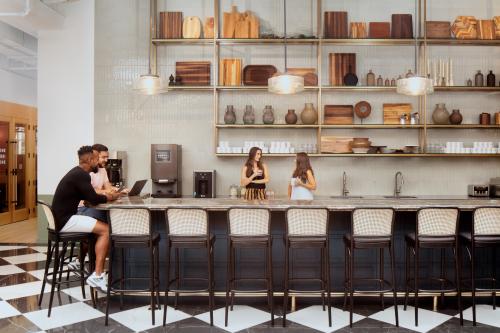 Ein moderner Büroraum in der Grünstraße 15, Düsseldorf Altstadt, mit Personen, die Gespräche führen und Laptops an einer stilvollen Bar nutzen. Perfekt, um ein Büro zu mieten.
