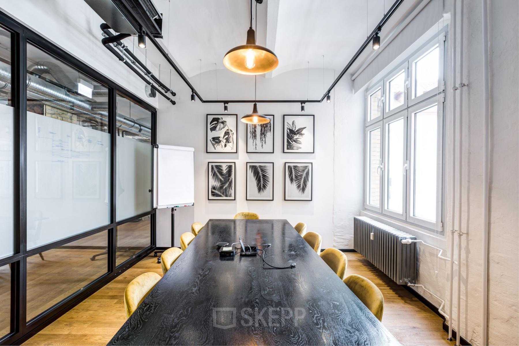 Moderner Besprechungsraum im Büro in der Grünstraße 15, Düsseldorf Altstadt (Königsallee), mit Holztisch, gelben Stühlen und Pflanzenbildern an der Wand.