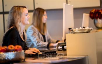Geschäftige Atmosphäre im modernen Büro an der Königsallee 27, Düsseldorf Altstadt. Zwei Personen arbeiten konzentriert am Computer. Perfekt zum Büroraum mieten.