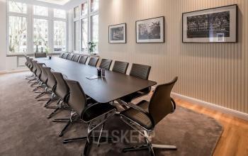 Moderner Konferenzraum in der Königsallee 27, Düsseldorf Altstadt. Ein langer Tisch mit eleganten Stühlen, umgeben von großen Fenstern, ideal für Meetings. Perfekt für büroraum mieten.