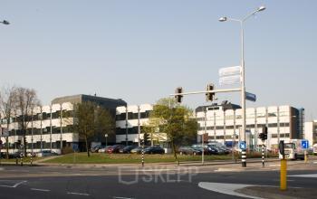 Modern office space rental at Galvanistraat 1, Ede, with a spacious parking area and a distinctive architectural design.