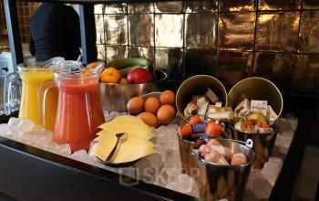 Breakfast setup at the office in Eindhoven Airport, featuring a selection of juices, fruits, cheeses, and condiments on ice. Ideal for office space rental events or meetings.