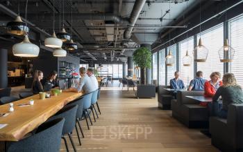 Modern and inviting workspace at Flight Forum 760-780, featuring sleek tables, ample natural light, and professionals engaging in discussions. Ideal for office space rental in Eindhoven Airport.