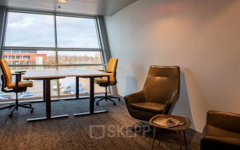 Cozy workspace at Flight Forum 760-780, Eindhoven Airport, featuring ergonomic chairs and a spacious desk bathed in natural light, ideal for office space rental.