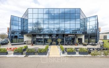 Modern office building at Luchthavenweg 81 with sleek glass facade, ideal for office space rental at Eindhoven Airport.