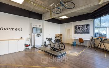 Modern furnished office space featuring cycling equipment and a workspace area at Luchthavenweg 81, ideal for office space rental near Eindhoven Airport.