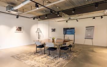 Furnished office space rental at Eindhoven Airport with modern decor, featuring a conference table, chairs, and a TV screen for meetings.