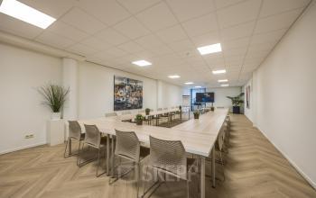 Spacious and well-lit conference room available for office space rental at Luchthavenweg 81, Eindhoven Airport, featuring a large table and chairs.