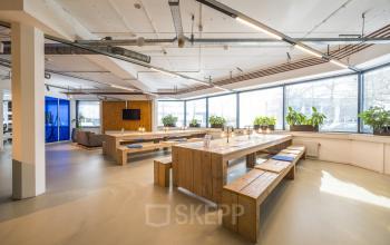 Bright and open office space with wooden tables and benches at Luchthavenweg 81, Eindhoven Airport. Ideal for office space rental with large windows and modern lighting.