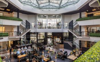 Spacious office to rent at Luchthavenweg 81, Eindhoven Airport, featuring an open-floor plan with multiple individuals engaging in business conversations and activities, ideal for office space rental.