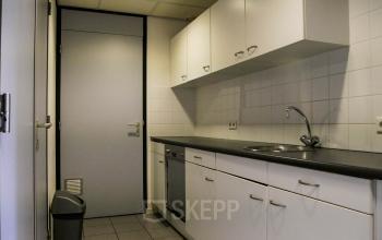 Office kitchen area with white cabinets and countertops, sink, and dishwasher, located at Luchthavenweg 55, Eindhoven Airport, suitable for office space rental.