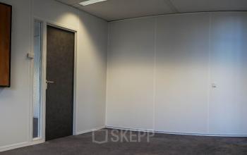 Unfurnished office space available for rent at Luchthavenweg 55, located in Eindhoven Airport, featuring clean white walls, a carpeted floor, and a door leading to an adjacent room.
