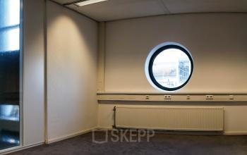 Office space available to rent at Luchthavenweg 55, Eindhoven Airport, featuring a round window and neutral decor.