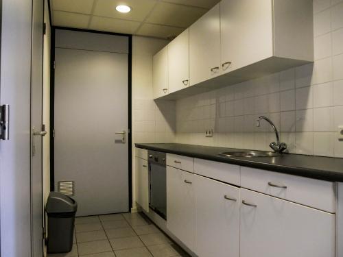 Office kitchen area with white cabinets and countertops, sink, and dishwasher, located at Luchthavenweg 55, Eindhoven Airport, suitable for office space rental.