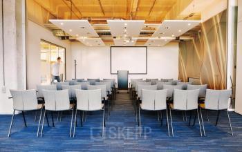 Conference room at Lichttoren 32, Eindhoven Center, ideal for office space rental, featuring rows of chairs and a projector screen setup.