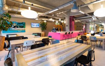 Modern, furnished office space at Lichttoren 32, Eindhoven Center featuring large wooden tables and a vibrant seating area, ideal for office space rental.