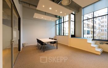 Bright office space at Lichttoren 32, Eindhoven Center with large windows and a meeting table, ideal for office space rental.