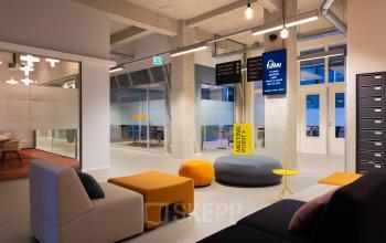 Modern furnished office space for rent at Lichttoren 32, Eindhoven Center, featuring colorful seating, a digital sign, and meeting room access.