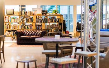 Inviting office space rental at Bogert 1, Eindhoven Center, featuring a cozy lounge area with eclectic furnishings and a bookshelf.