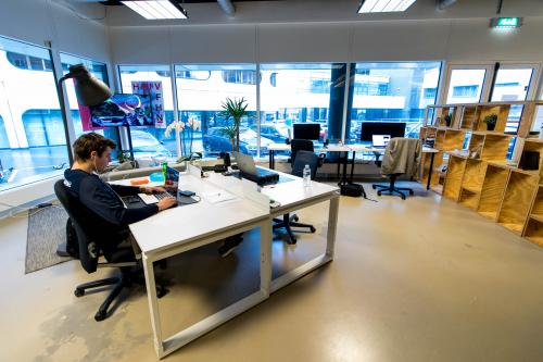 Comfortable office space rental at Bogert 1, Eindhoven Center, with a person focused on business tasks at a clean workstation amidst modern decor.