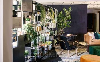 Modern office lounge at Emmasingel 33, Eindhoven Center, featuring stylish seating, plants, and decorative shelving, ideal for relaxation or informal meetings. Perfect for those looking to rent office space in a vibrant environment.