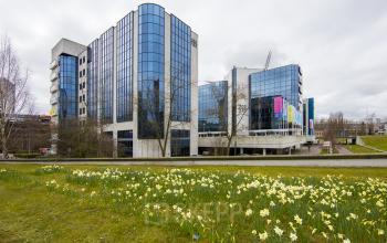 Modern office space available for rent at Fellenoord 130, Eindhoven Center, with mirrored glass facade reflecting vibrant surroundings.