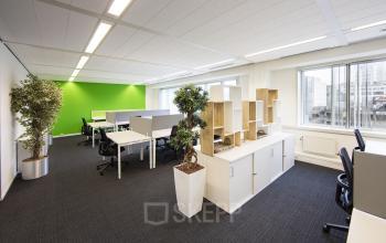 Bright and well-lit office space rental at Fellenoord 130, Eindhoven Center, with organized workstations and vibrant green accent walls.