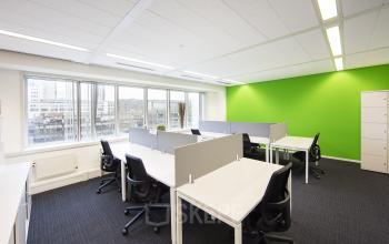 Modern office space rental at Fellenoord 130, with well-lit workstations and vibrant green accent walls in Eindhoven Center.