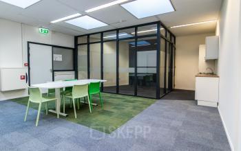Modern office space at Paradijslaan 30-38, Eindhoven Center with meeting table and chairs, glass-walled conference room, and kitchenette.