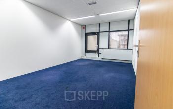Office space rental at Paradijslaan 30-38 in Eindhoven Center, showcasing an empty, carpeted office room with ample natural light from large windows.