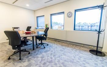 Office space rental at Paradijslaan 30-38, Eindhoven Center with a round meeting table, chairs, coat rack, and large windows.