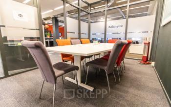 Contemporary conference room with a white table, colorful chairs, and glass partitions at an office space rental in Paradijslaan 30-38, Eindhoven Center.