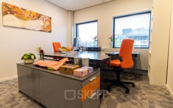 Well-lit office to rent at Paradijslaan 30-38, Eindhoven Center, with two desks, orange chairs, and vibrant decor.