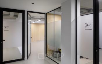 Spacious office hallway at Paradijslaan 30-38 in Eindhoven Center, featuring modern glass doors. Ideal for office space rental with easy navigation between rooms.