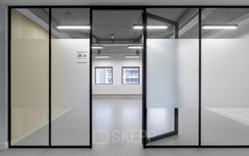 A modern office space rental in Eindhoven Center with frosted glass partitions and large windows offering natural light, suitable for businesses looking to rent office space.