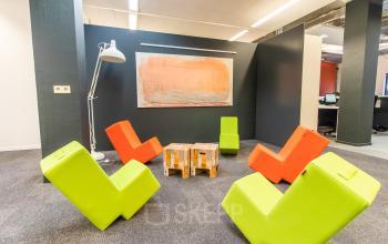 Colourful lounge area with modern chairs and a unique artwork on the wall, located in the Paradijslaan 30-38 office building in Eindhoven Center.
