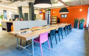 Colorful and modern office space rental at Paradijslaan 30-38, Eindhoven Center featuring a long wooden table with various chairs, open shelving, and vibrant decor.