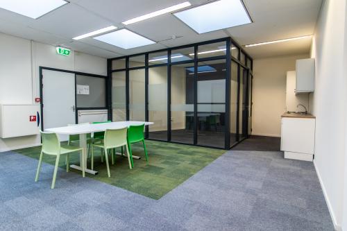 Modern office space at Paradijslaan 30-38, Eindhoven Center with meeting table and chairs, glass-walled conference room, and kitchenette.